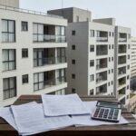 Condomínio residencial brasileiro com documentos fiscais representando cálculo de ganho de capital imobiliário