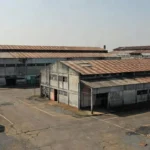 Complexo industrial envelhecido no Brasil com galpões antigos, análise de custo de reposição e cap rate